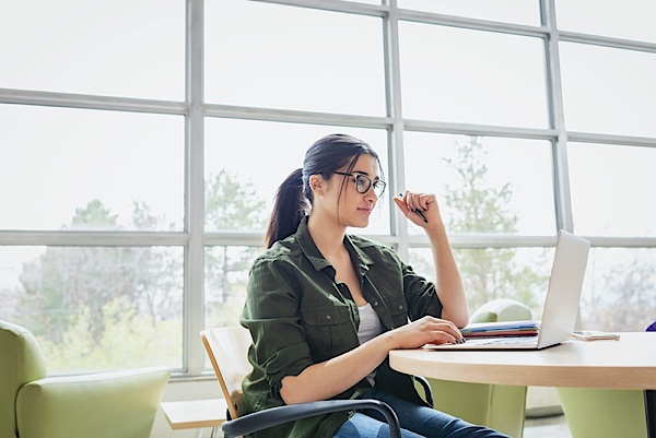 Woman using laptop in a room with big windows