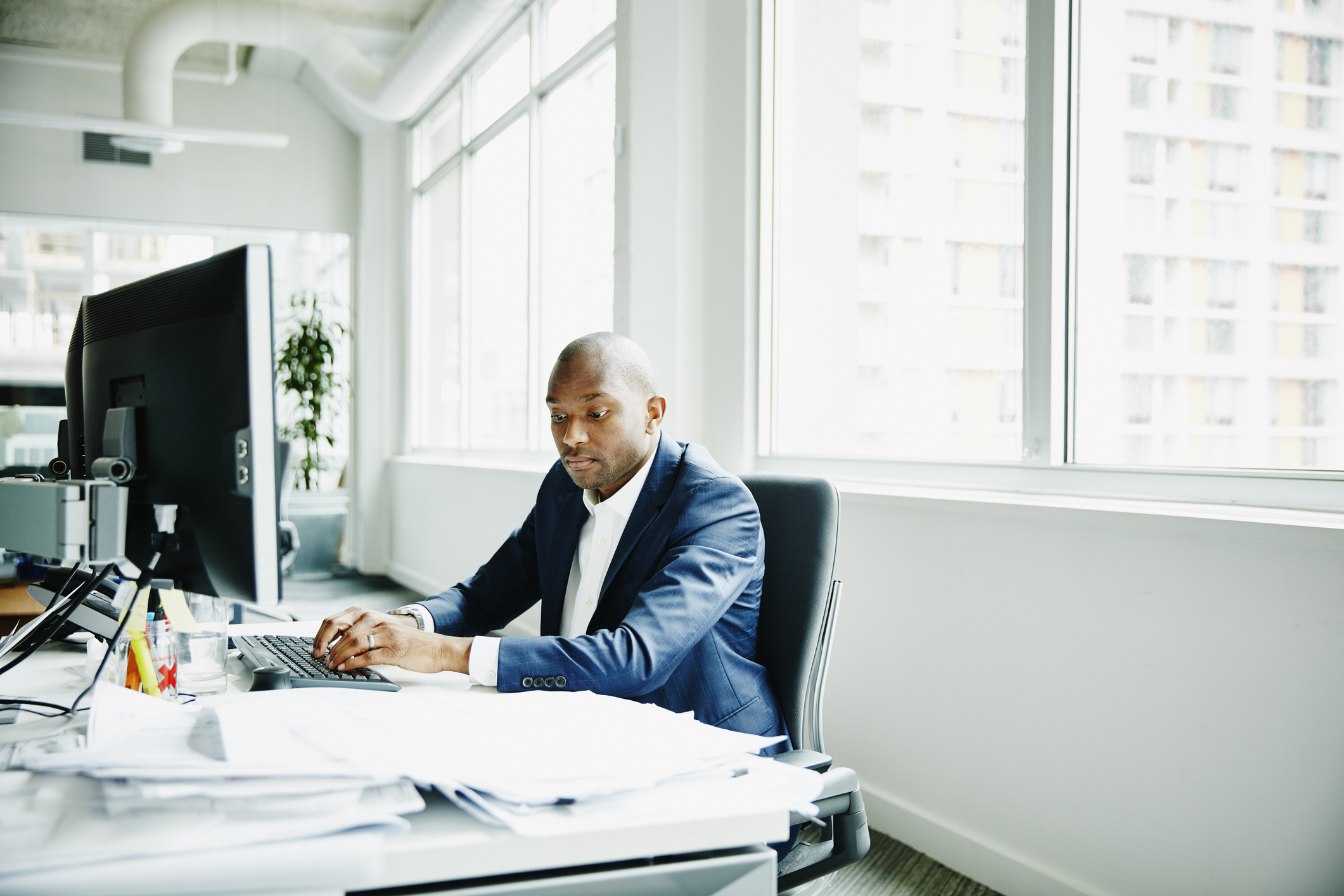 Man working on computer looking at papers