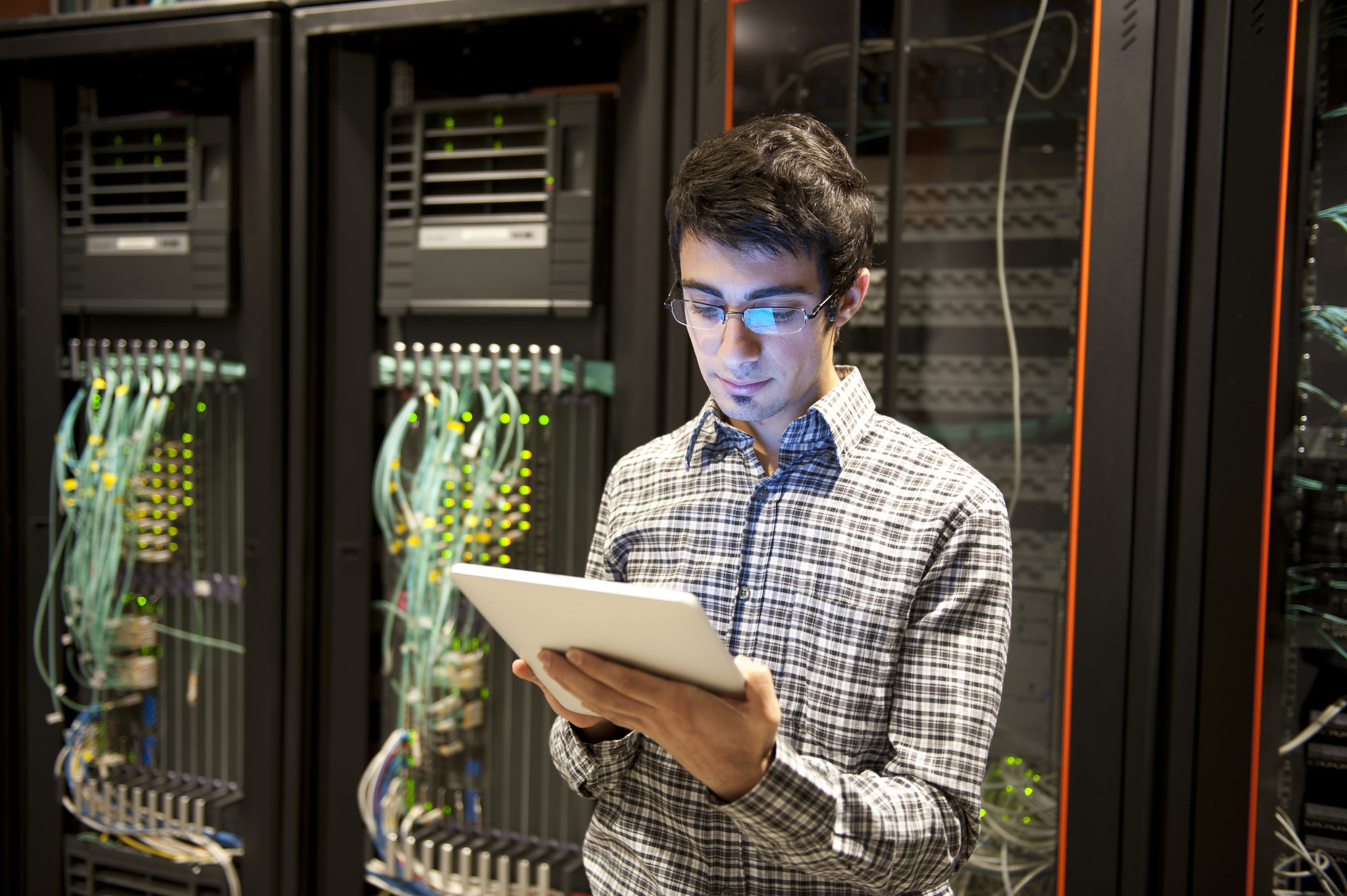 Person using tablet in room with network hardware